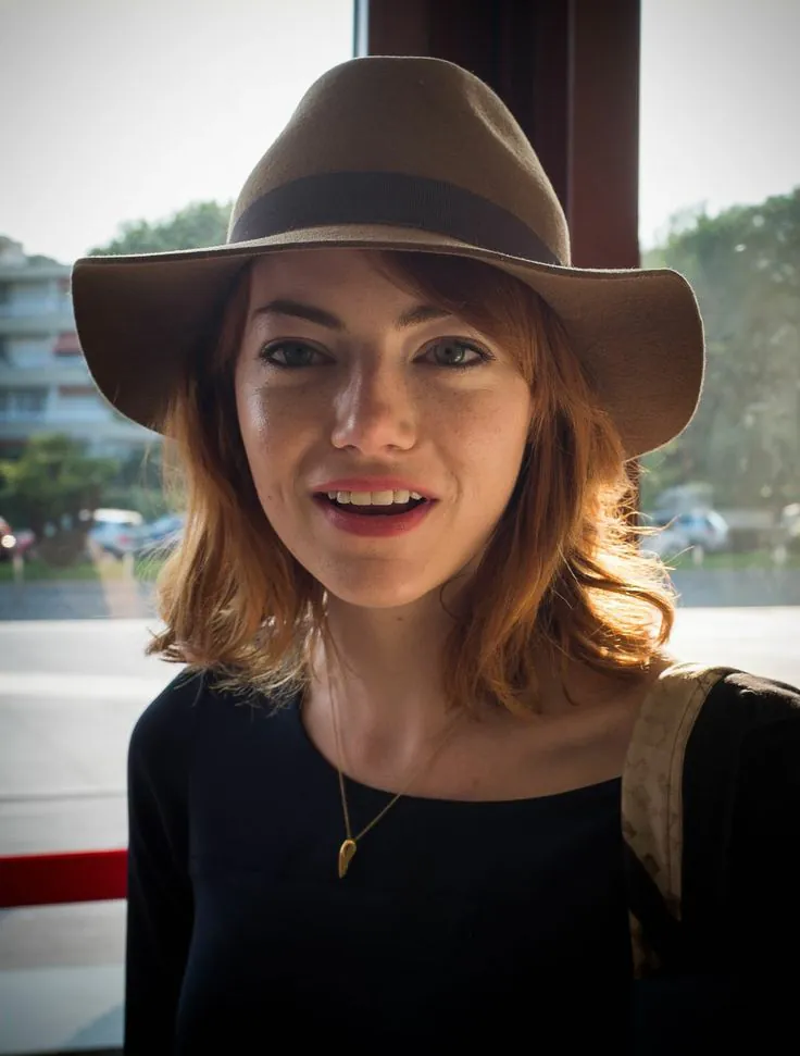 Emma Stone thường đội mũ lệch kết hợp tóc rẽ ngôi lệch để tạo hiệu ứng thon mặt.
Ảnh: Getty Images