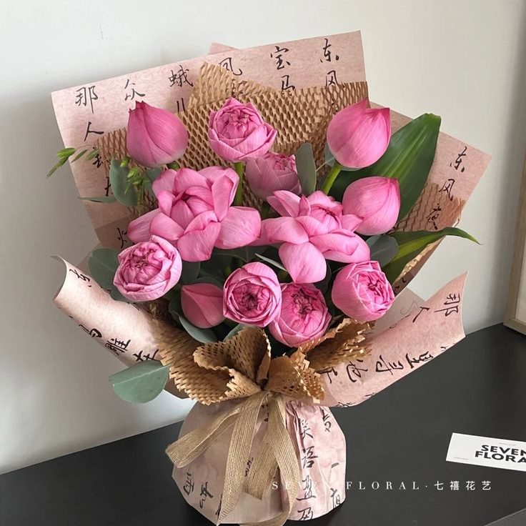 Phom dáng búp sen nở rộ, được gói trong giấy họa tiết thư pháp màu hồng đất và giấy nhún, mang lại cảm giác cổ điển và nét đẹp truyền thống. Ảnh: internet.