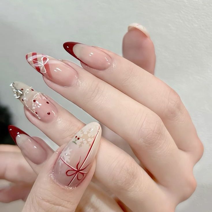 Mẫu nails đỏ trầm cùng họa tiết nơ mảnh và hoa tuyết tạo nên vẻ sang trọng tinh tế. Ảnh: internet.
