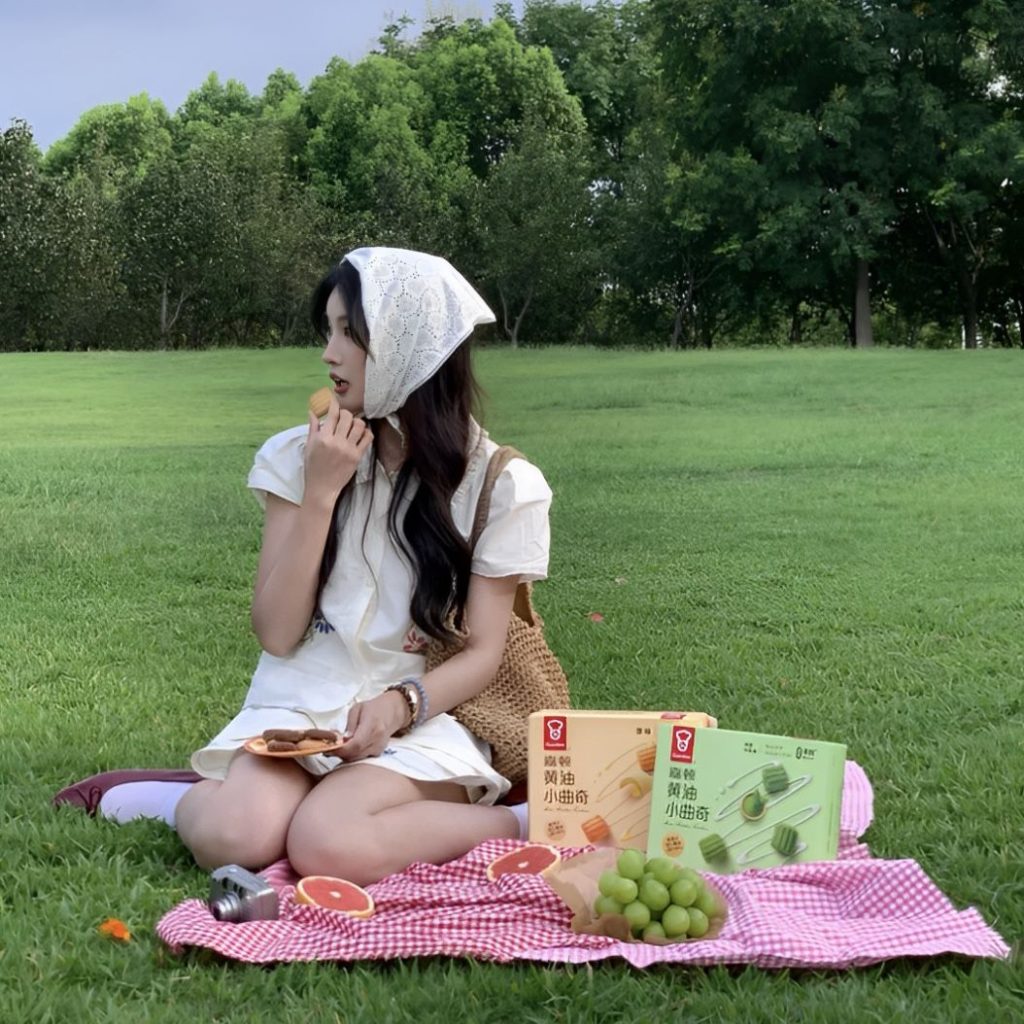 Khoảnh khắc thưởng thức bánh quy và trái cây giữa thiên nhiên xanh mát - pose dáng trên bãi cỏ Ảnh: internet.